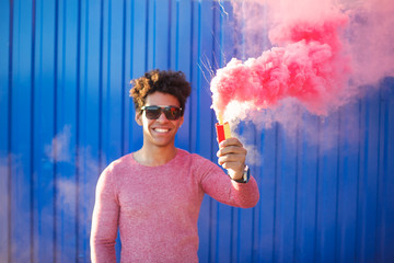 Happy cheerful man holding a smoke grenade