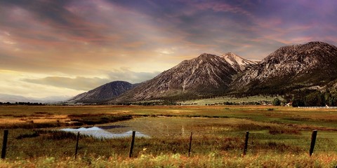 Golden sunset hour over rugged Sierra Nevada mountains with natural pond.