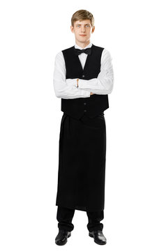 Full length portrait of young handsome waiter standing with cros