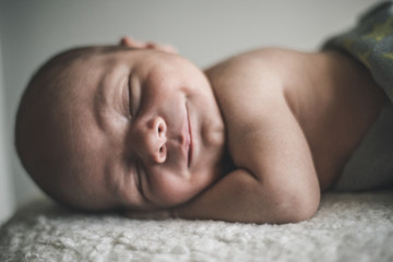 Portrait of sleeping smiling newborn baby close up