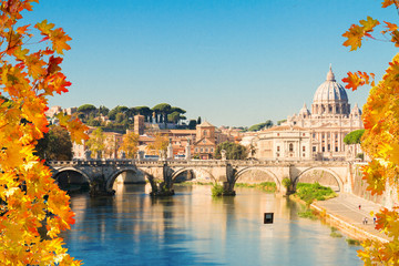Fototapeta na wymiar St. Peter's cathedral over bridge and river water at fall day in Rome, Italy