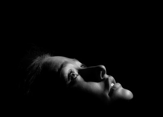 face of girl looks up in dark monochrome image