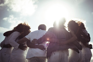 Low angle view of friends with arm around standing against sky