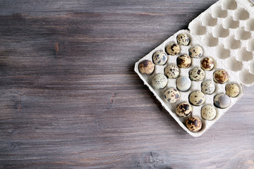 Cardboard egg rack with quail eggs on wooden table. Symbol of superfood, healthy natural eating.