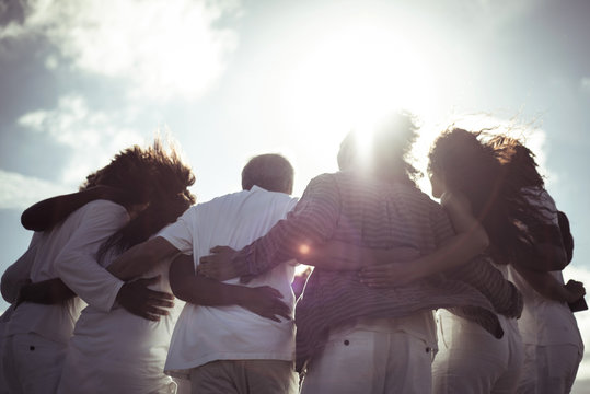 Low angle view of friends with arm around standing against sky