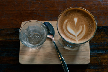 hot fresh coffee in see through glass water glass on wooden tray and table silver spoon at coffee time / hot fresh coffee