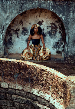 Woman sat cross legged in patterned headdress and skirt 