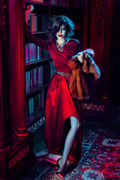 Woman in red dress standing holding fur 