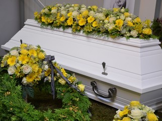 Weißer Sarg dekoriert mit vielen Blumen - Rosen, Gerbera, Lilien, Inkalilien in Gelb