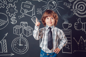 Little boy as businessman or teacher wearing shirt and tie lifting a finger up on dark background with business school picture