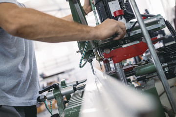 Manual worker cutting aluminum and PVC profiles. Manufacturing jobs. Selective focus. Factory for aluminum and PVC windows and doors production.