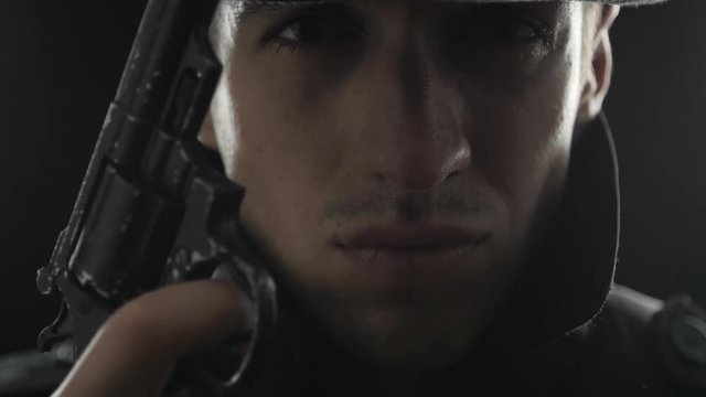 Close up Portrait of gangster in a hat and a black cloak with a gun