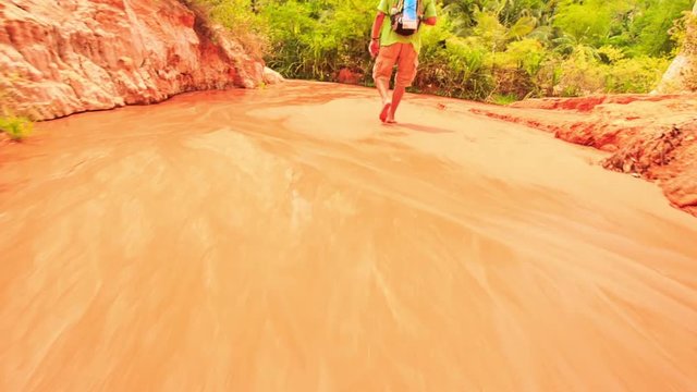 Tourist Walks Barefoot along Fairy-Stream Shallow Water