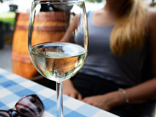 Wine glasses on table in the restaurant and in the background woman's hands
