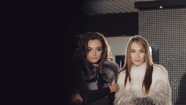 Two rich girls posing and catwalking in fur coats