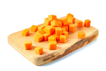 Sliced pumpkin cubes on wooden board ower white background