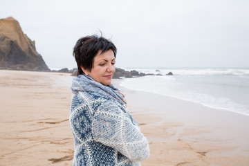 Single mature attractive woman standing on empty beach. Looking at the ocean. Rear view. Thinking. Adult healthy lifestyle. portrait