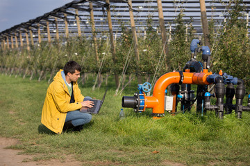 Engineer with irrigation system in orchard