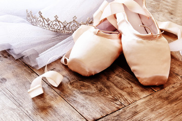 Image of silk pointe shoes and tutu on wooden floor