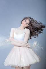 Fototapeta na wymiar Portrait of a beautiful girl in a white dress dancing with flour in the Studio