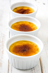 Traditional French creme brulee dessert with caramelized sugar on top, on white wooden table

