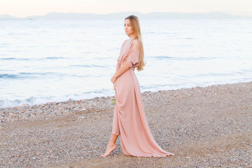 Young woman walking on the shore of the ocean with a sprig of olive