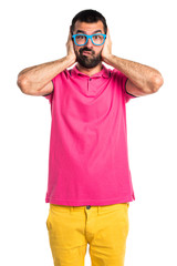 Man with colorful clothes covering his ears