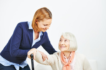 Caregiver helping senior woman getting up