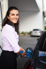 Obraz na płótnie Canvas Hispanic businesswoman refuel car