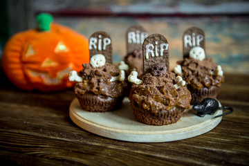 Halloween cupcakes with tombstone cake topper and candle on an old wooden table