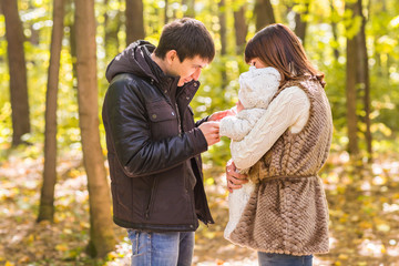 young family with their newborn baby spending time outdoor in the autumn park.