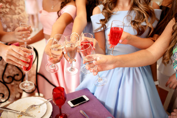 Hands of young girls decorated with manicure holding glasses filled with champagne at a party