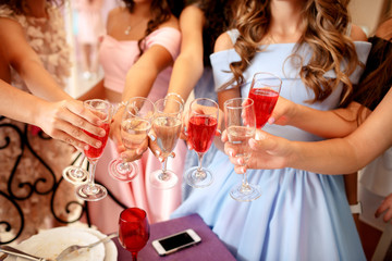Hands of young girls decorated with manicure holding glasses filled with champagne at a party