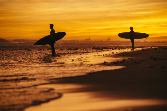 Surfing couple at sunset, Rincon, Santa Barbara, California, United States of America