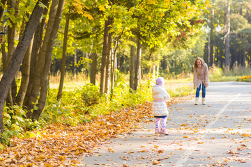 Fototapeta premium Adorable little kid girl and young woman in beautiful autumn forest. Daughter running to mother. Family portrait, fall season.