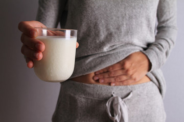 Woman with stomach pain holding a glass of milk. Dairy Intolerant person. Lactose intolerance, health care concept. - obrazy, fototapety, plakaty