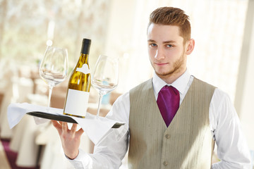 Waiter holding bottle of wine and glasses