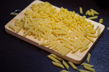 Pasta of different shapes on a wooden board