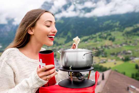 Young woman eating fondue a traditional swiss meal during a trip in the mountains in Switzerland