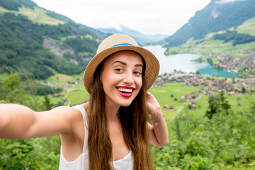 Young woman making selfie photo on the beautiful landscape background in Switzerland