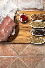 Fresh meat selection on wooden cutting board with spices in a white bowl