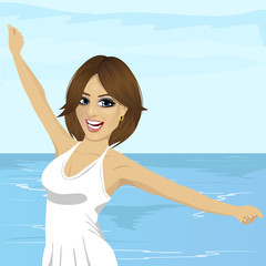 beautiful young caucasian woman with her hands raised at beach