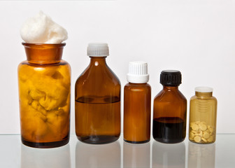 Vials of yellow glass with medicines and cotton wool are on a glass shelf