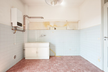 Old empty kitchen interior with tiled floor and walls