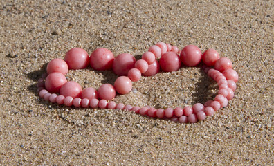 Pink coral beads lie on the sand