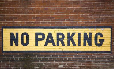 Dubuque, Iowa, October 2016: A no parking sign painted on a brick wall in the historic Millwork District in Dubuque, Iowa.