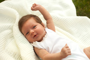 Baby smiling on the blanket on the grass