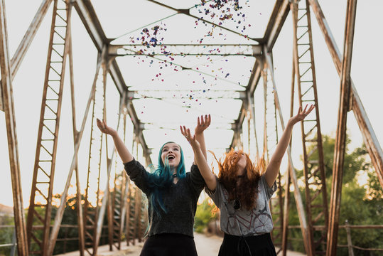 Happy teenage girls throwing up confetti in air