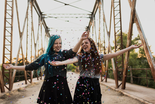 Happy teens throw up confetti in the air.
