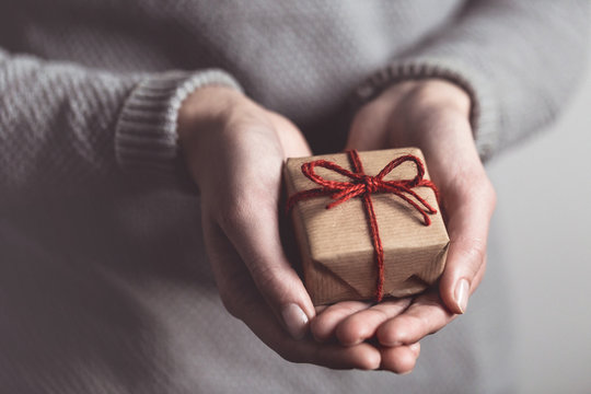 Close up of female hands holding small gift. Sharing concept. Christmas presents.